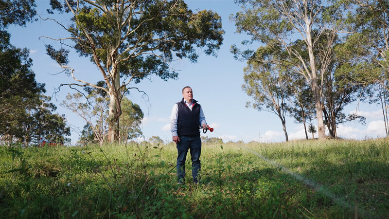 Man spraying weeds using a Rapid Spray poison sprayer, vehicle-mounted spray unit on a ute, demonstrating efficient spot spraying for weed control in rural or agricultural property.