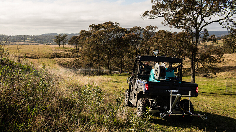 Alt Text: Man spraying weeds from inside a UTV using a Rapid Spray Marshal UTV-mounted sprayer on a rural property in Australia.