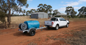 White Ford Ranger towing a Rapid Spray water trailer across a rural paddock in Australia