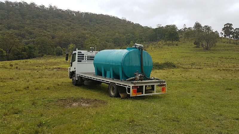 White water delivery truck fitted with a Rapid Spray cartage tank transporting potable water through a rural farm field in Australia.